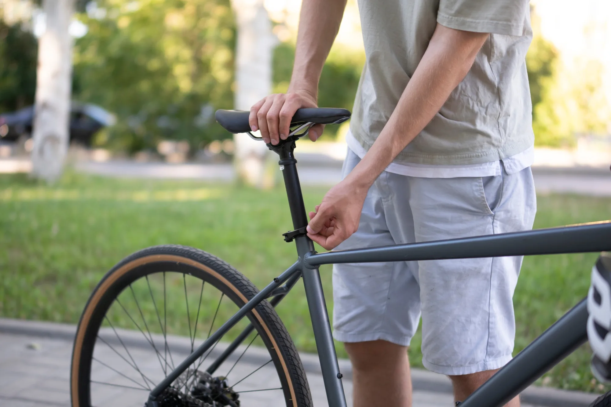 a man in a light-colored shirt adjusts the seat height of his bicycle.